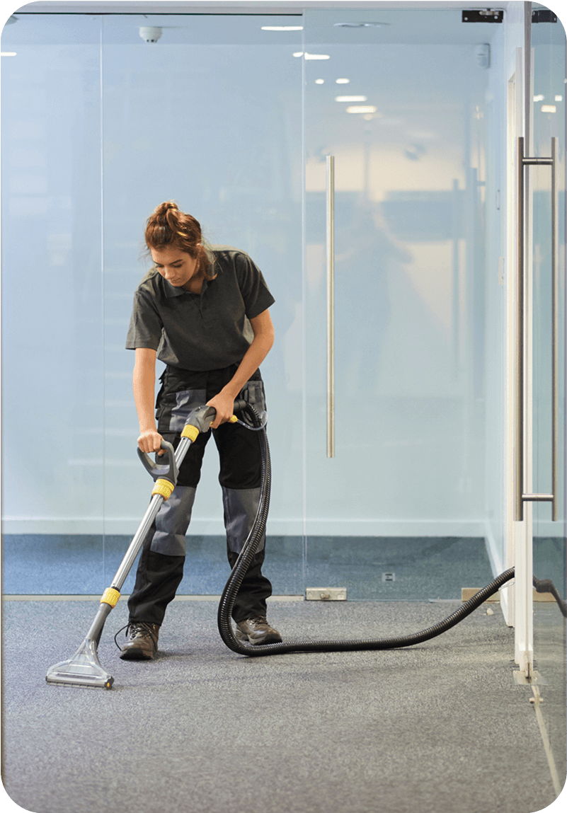 Person vacuuming office carpet with machine.